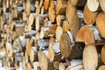 Stacked firewood with snow as background, closeup. Heating house in winter