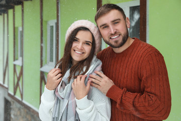 Lovely couple wearing warm sweaters outdoors on snowy day. Winter season