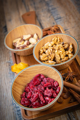 Mixed nuts and dried fruits in wooden bowl on wood background, copy space