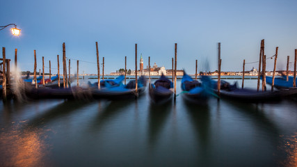 Gondolas by Saint Mark square with San Giorgio di Maggiore church in Venice at sunset