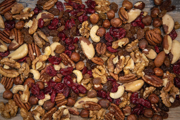Mixed nuts and dried fruits in wooden bowl on wood background, copy space