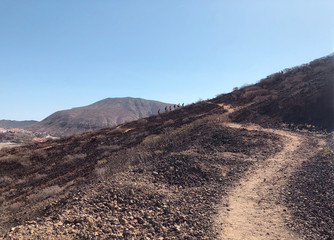 view of hiking desert trail with hikers away over mountain background