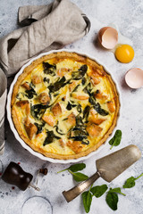 Homemade quiche tart with red fish and spinach on light wooden background. Vintage style. Top view.
