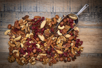 Mixed nuts and dried fruits in wooden bowl on wood background, copy space