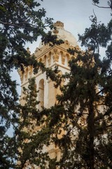 Tower of catholic cathedral of St. Louis in Carthage, Tunisia, view through the leaves of trees