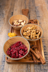Mixed nuts and dried fruits in wooden bowl on wood background, copy space