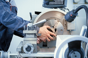 A worker drills a steel part