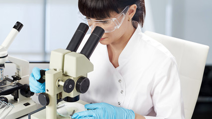 A young female laboratory assistant in a white uniform