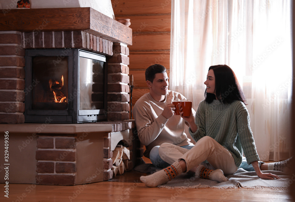 Canvas Prints Lovely couple with delicious cocoa near fireplace on floor at home. Winter vacation