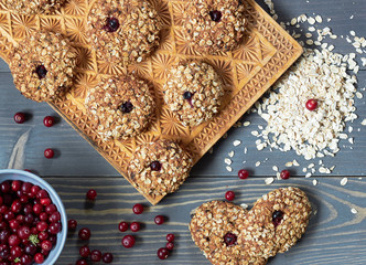 Oatmeal homemade cookies with cranberry flat on wooden table with berries and oats nearby, from above overhead top view, closeup, copy space