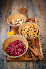 Mixed nuts and dried fruits in wooden bowl on wood background, copy space