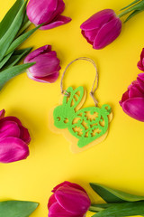 Easter concept. tulips, easter bunny and colored eggs on a yellow background