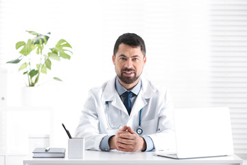 Portrait of male doctor in white coat at workplace