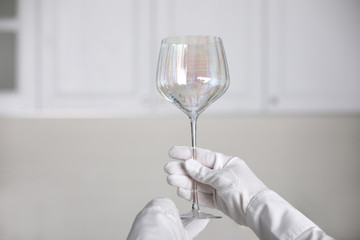 Person in white gloves checking cleanliness of glass indoors, closeup. Space for text