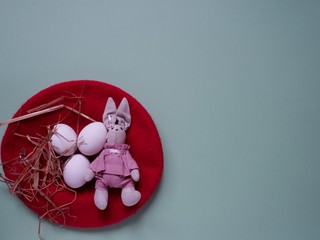 festive Easter layout of three eggs in a straw basket with a rabbit on a colored background