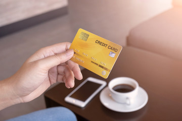 Woman holding credit card in coffee shop. Warm tone.