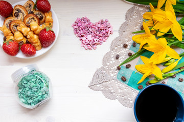 Valentine's day strawberry cookies hearts with coffee, with yellow flowers on a napkin for a note