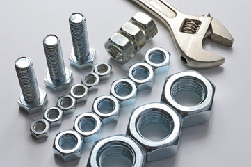 screw-nut of different sizes, bolts and adjustable spanner. White background. Concept.