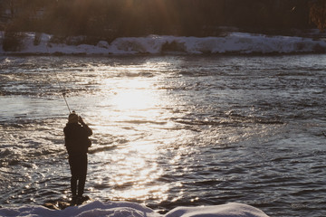 A man fly fishing on the bank of a river
