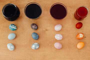 Obraz na płótnie Canvas Natural dye easter eggs. Colorful painted easter eggs on wooden table, pink egg - with beetroot, turquoise - red cabbage, orange and yellow - onion or turmeric, grey and purple - with carcade tea