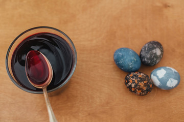 Modern grey, dark and stone marble easter eggs painted with carcade tea, glass jar with dark red color. Zero waste holiday. Organic ingredients. Natural dye easter eggs on wooden table.