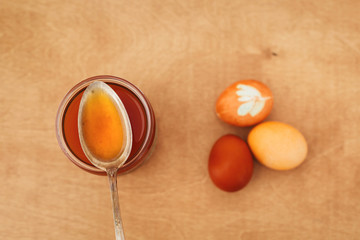 Modern pastel yellow and orange easter eggs painted with onion or turmeric, glass jar with orange color. Zero waste holiday. Organic ingredients. Natural dye easter eggs on wooden table.