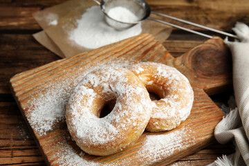 Delicious donuts with powdered sugar on wooden table