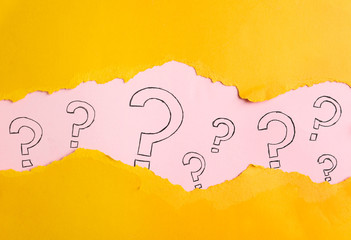 Question marks on pink background, view through hole in yellow paper