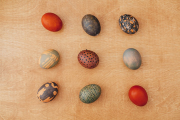Modern Easter eggs flat lay on rustic wooden background. Stylish brown and stone Easter eggs with modern ornaments painted in natural dye of carcade tea and onion. Happy Easter