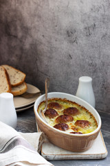 Baked meatballs in a creamy sauce and slices of bread with flax on a concrete background.