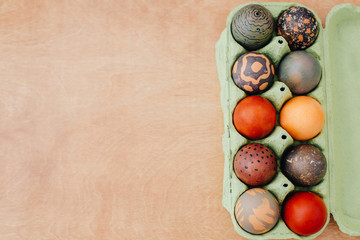 Stylish Easter eggs natural dye in carton tray on rustic table, flat lay. Modern marble, brown and red easter eggs painted with organic onion and carcade tea. Zero waste holiday. Copy space