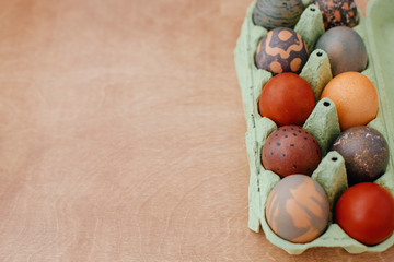 Modern marble, brown and red easter eggs painted with organic onion and carcade tea. Zero waste holiday. Stylish Easter eggs natural dye in carton tray on rustic table, flat lay.  Copy space