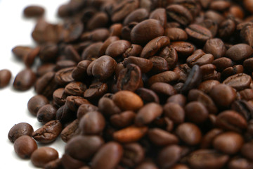 An isolated pile of roasted coffee beans on a white background surface