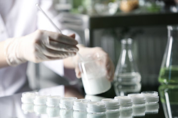 Scientist working in cosmetic laboratory, focus on jars with cream