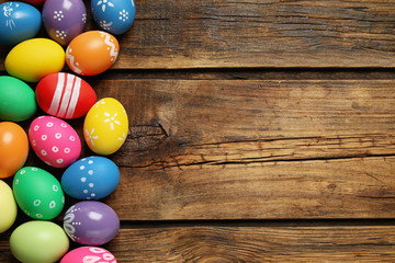 Fototapeta na wymiar Colorful Easter eggs on wooden background, flat lay. Space for text