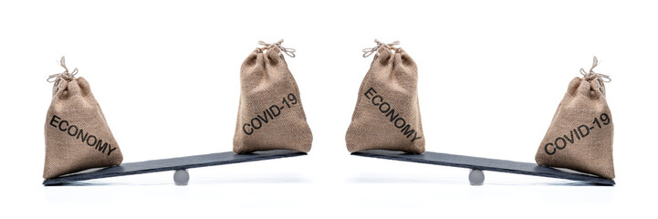 Gefahren für die Wirtschaft durch das Coronavirus symbolisiert durch eine Waage mit den Texten ECONOMY und COVID-19