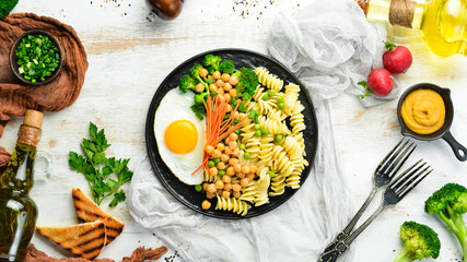 Pasta with vegetables and fried egg on a black stone plate. Bowl Buddha. Top view. Free space for text.