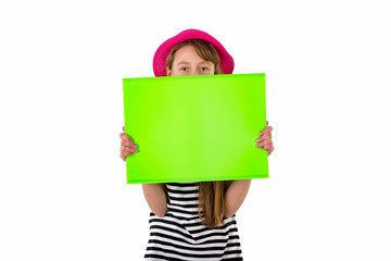 Joyful cheerful long haired teenage caucasian girl wearing a red hat horizontal black and white striped t-shirt shows to green sheet of folder with a mockup for advertising on white studio background