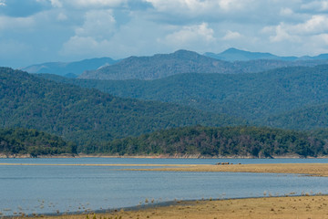 Wild elephant family Beautiful scenery picturesque landscape with scenic view of Ramganga River, clouds, mountain and hills of dhikala zone at jim corbett national or tiger reserve, Uttarakhand, India