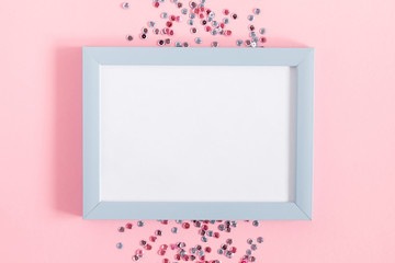 Festive pink background. Empty photo frame for text, confetti on light pink pastel background. Christmas. Wedding. Birthday. Flat lay, top view, copy space.