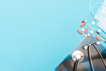 Chest x-ray film, stethoscope, sterile surgical masks and assortment of medical capsules and pills on light blue background with copy space for your text. Infection prevention concept. Health care.