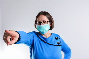 a pensive woman with a surgical mask pointing her finger to you. Virus infection, shortness of breath. Causes of cough include pneumonia, bronchitis, allergy, asthma, or respiratory tract infection.