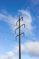 low voltage power line against a background of blue sky and clouds. electric pole