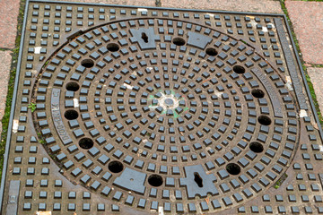 Manhole cover walled in cobblestones on the street