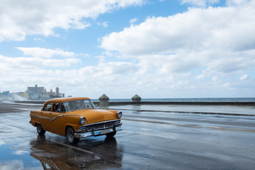 Classic orange car driving through the streets of Havana
