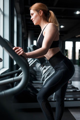 Obraz na płótnie Canvas Slender woman training on a fitness simulator
