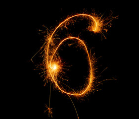 number six written with a sparkler on a black background