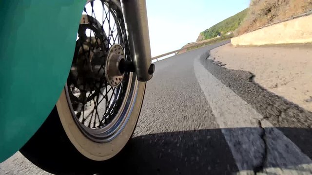Motorcycle ride on a winding coastal road seen from the front w. Sardinia, Italy