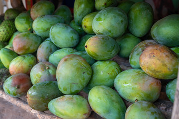 Red and green mango stack at grocery on tropical marketplace outdoor,Samana peninsula,Dominican republic.