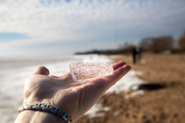 A piece of ice on a female hand.